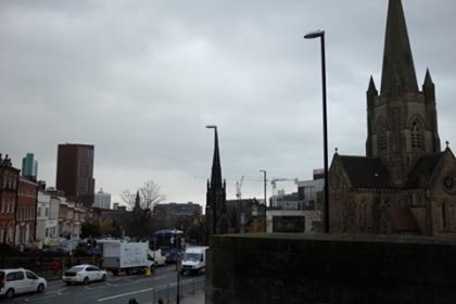 A view of buildings and a church in Leeds, looking very dark and overcast