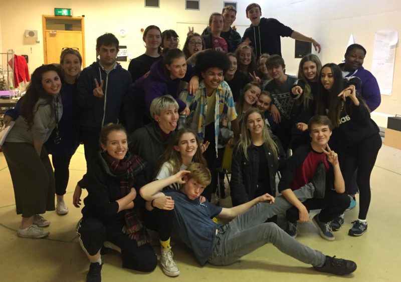 Group of young adults looking relaxed, smiling at the camera and doing peace signs