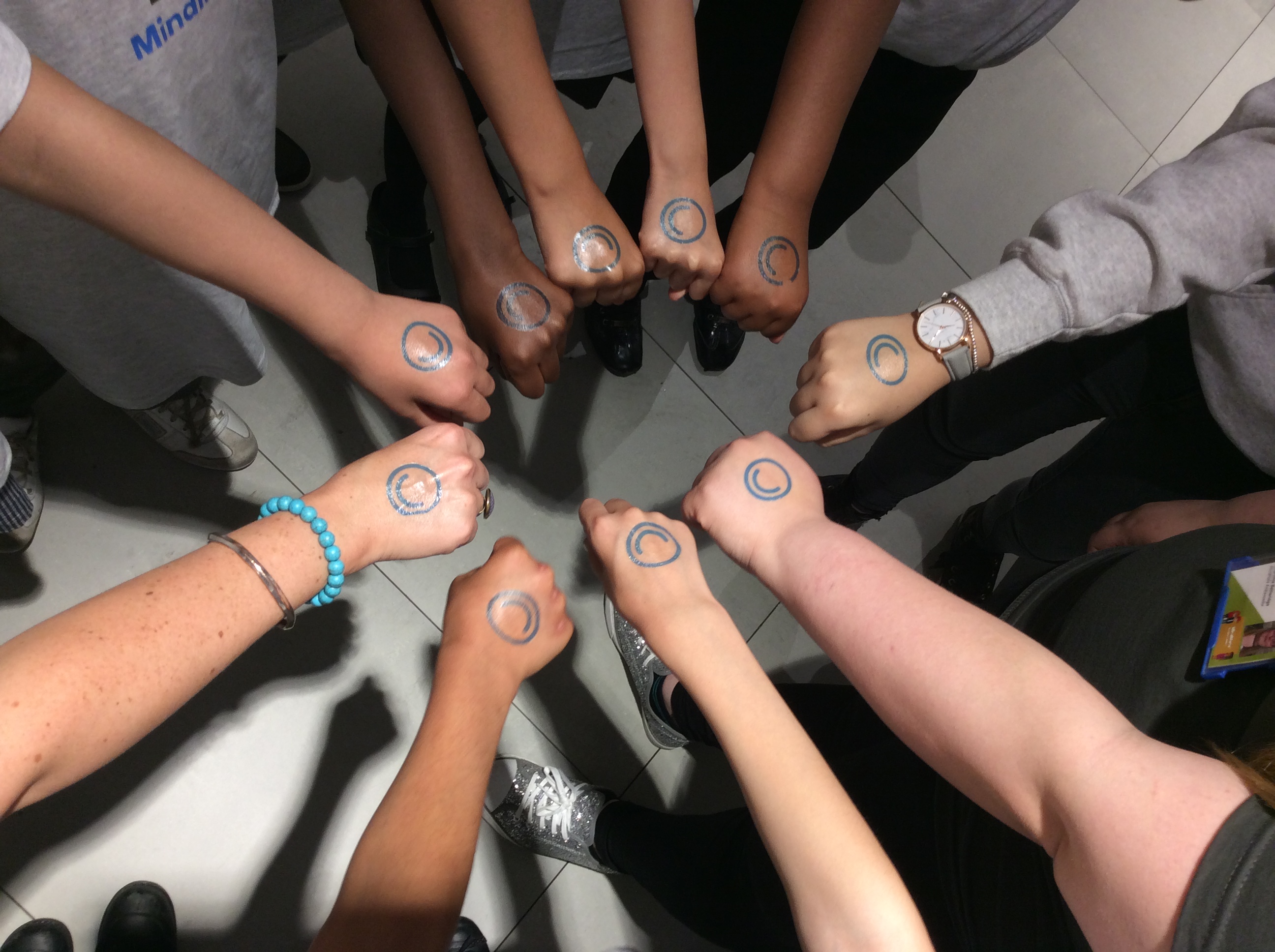 Young people with their hands together and the MindMate logo stamped on their hands