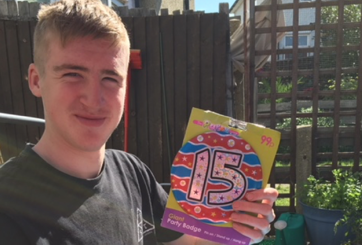 Young man holding a 15 year old birthday badge